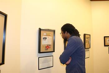man looking closely at framed artifacts on wall
