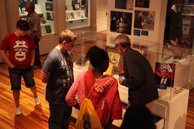 children and adult looking at exhibits in glass cases
