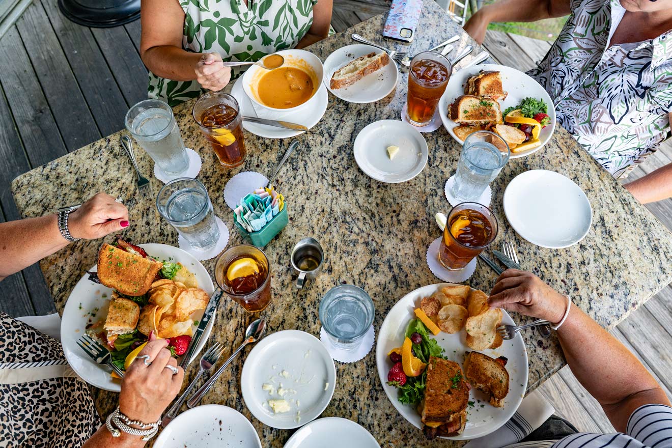 Four ladies eat various dishes at an outdoor table from Brave New Restaurant in Little Rock, AR.