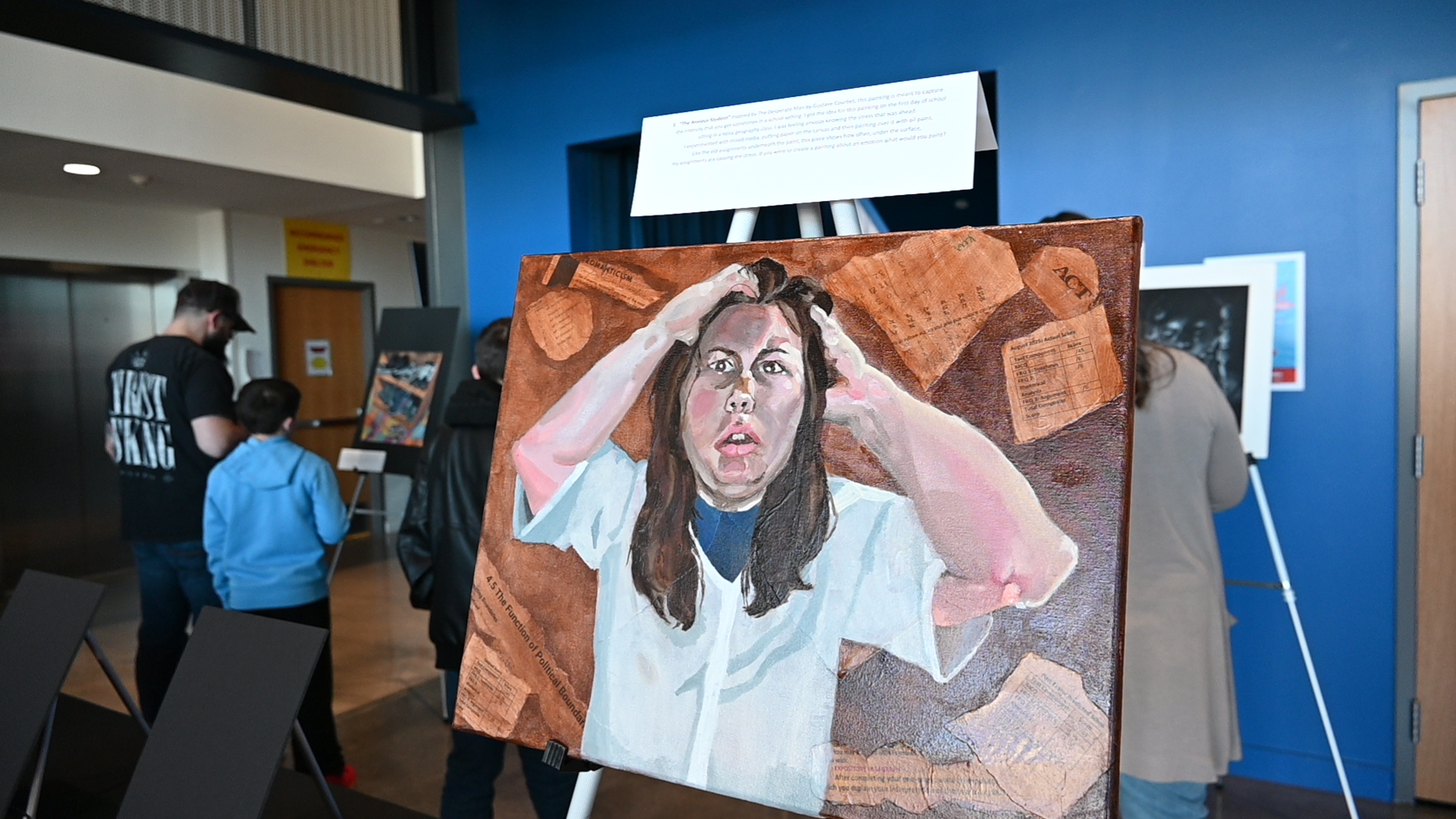 A student stands beside her artwork