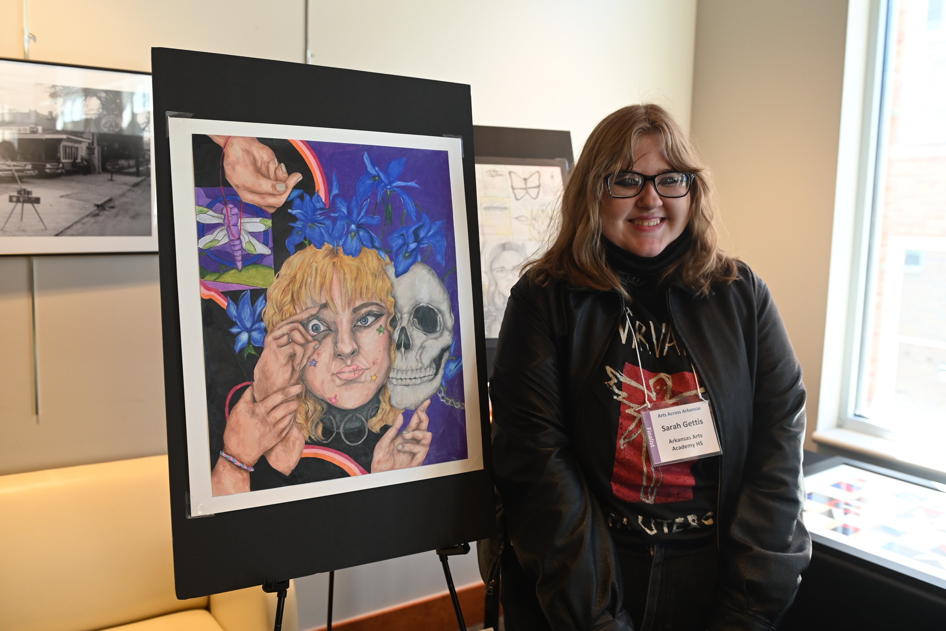 A student stands beside her artwork