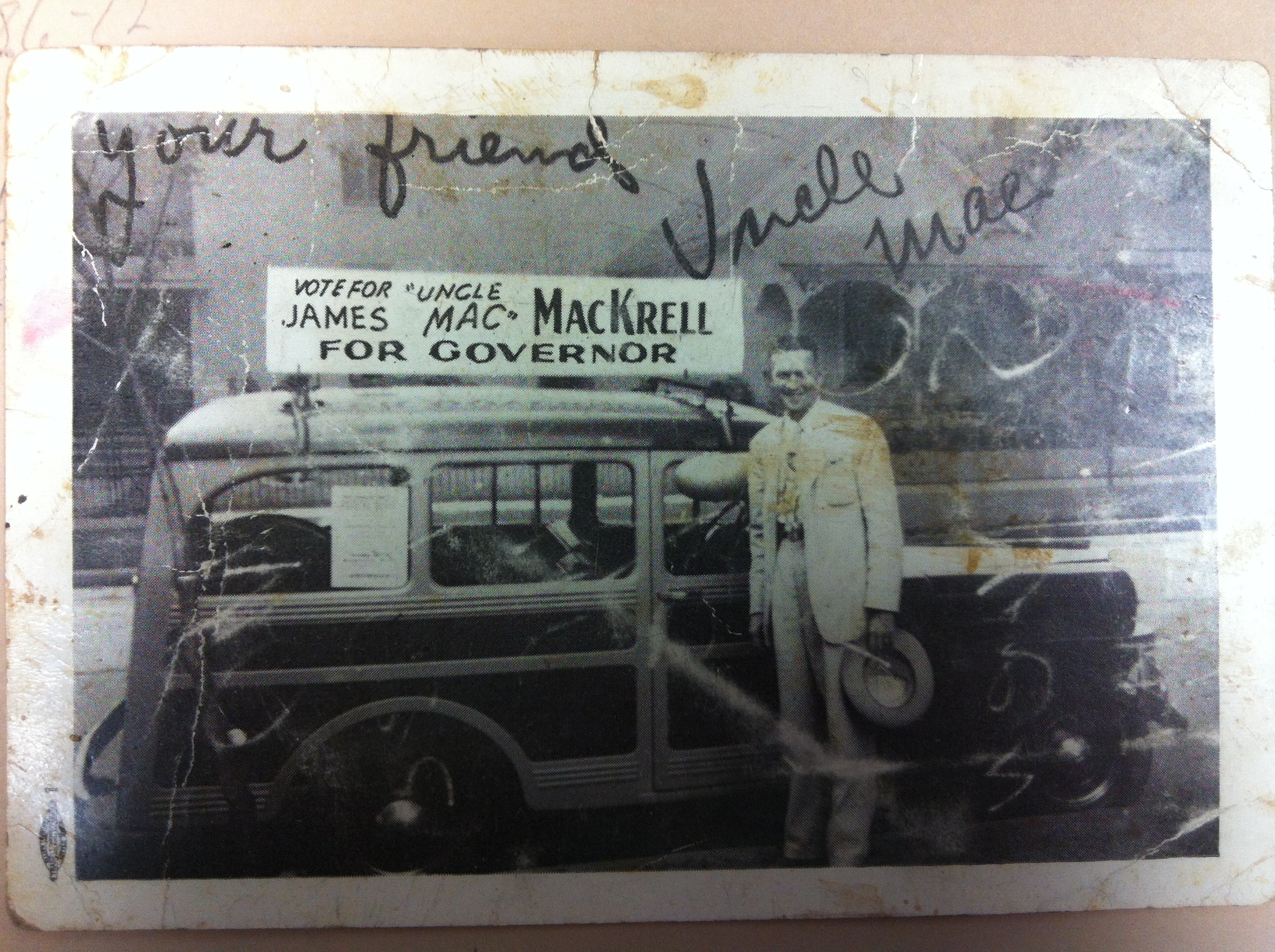A man standing in front of an old automobile with superimposed text reading "Vote for Uncle James Mac MacKrell for Govornor".