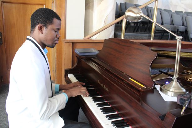 man in suite sitting at piano playing it