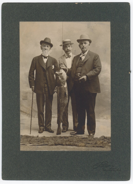 photograph of three men dressed in suits with a fish