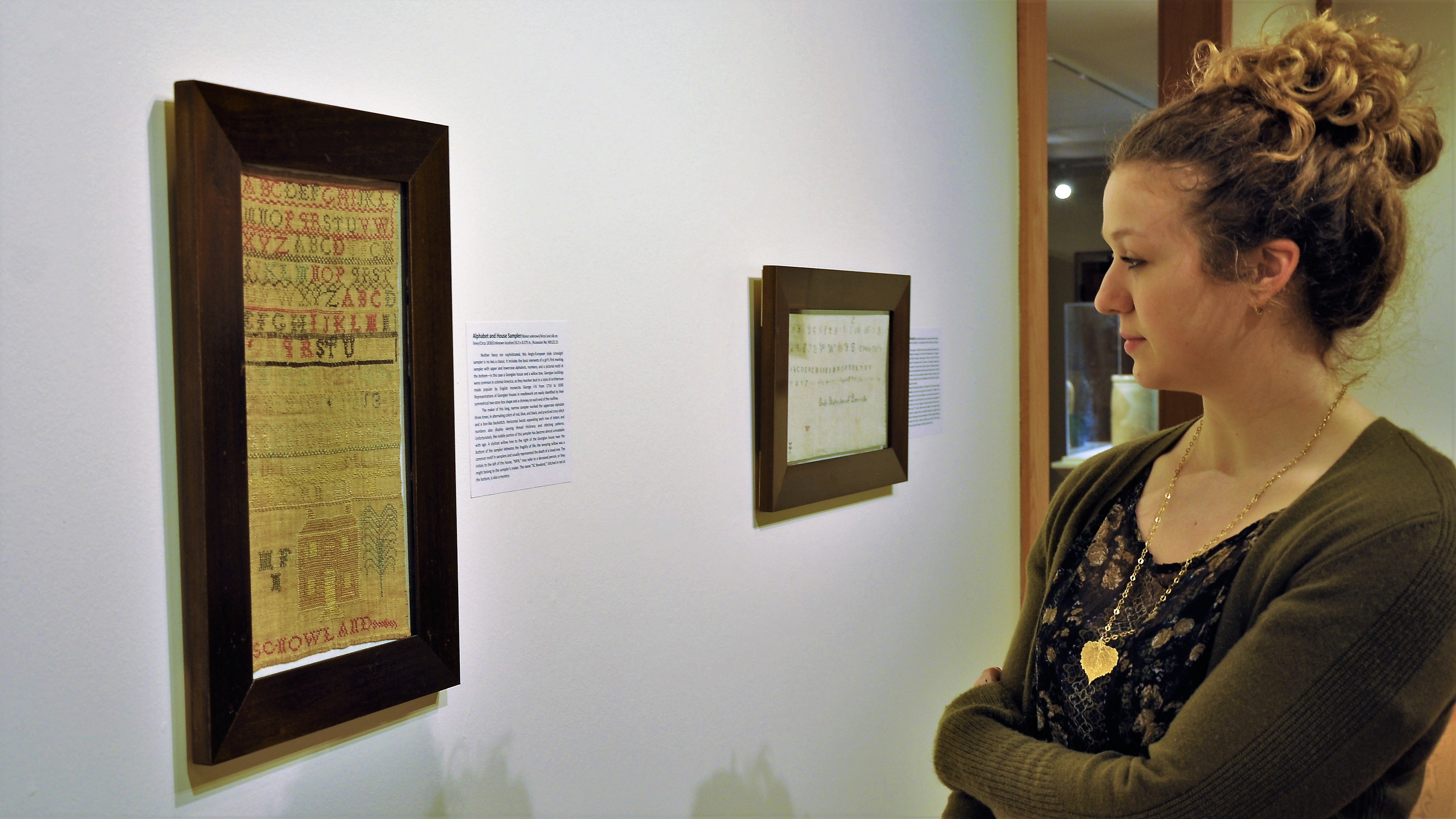 woman looking at threaded art piece on wall of gallery