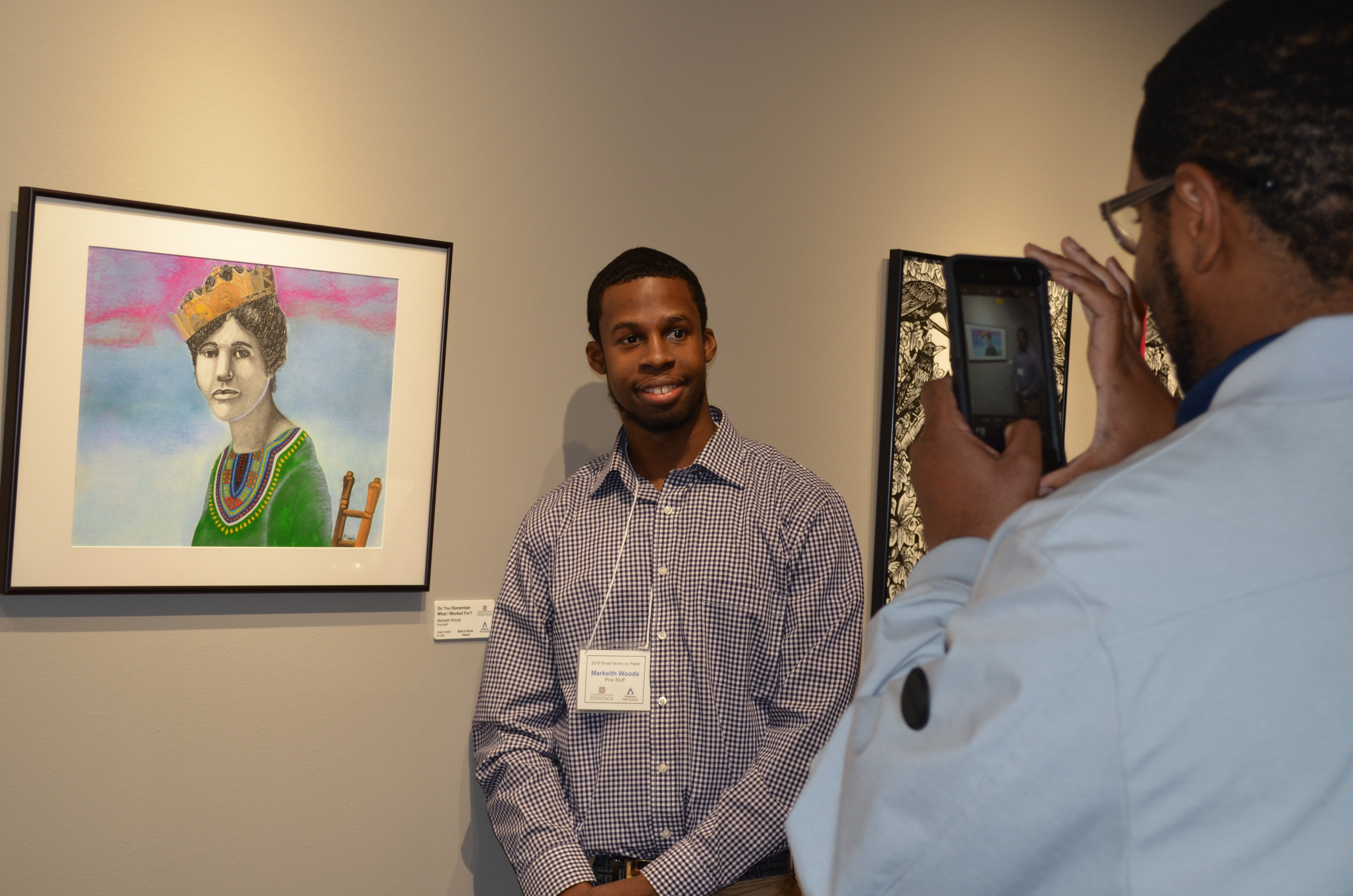 man standing by art on wall getting picture taken