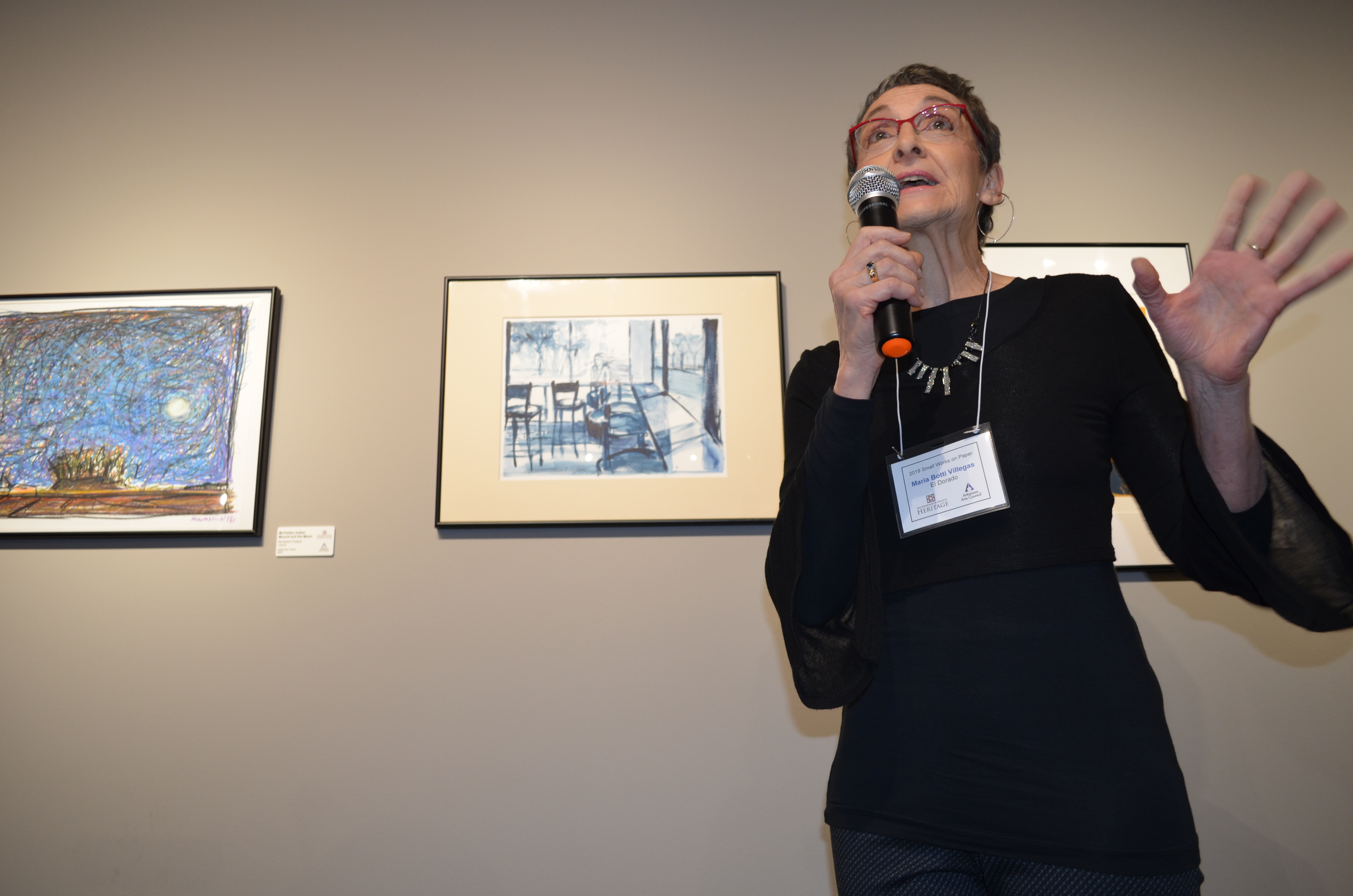 woman holding microphone and speaking with art behind