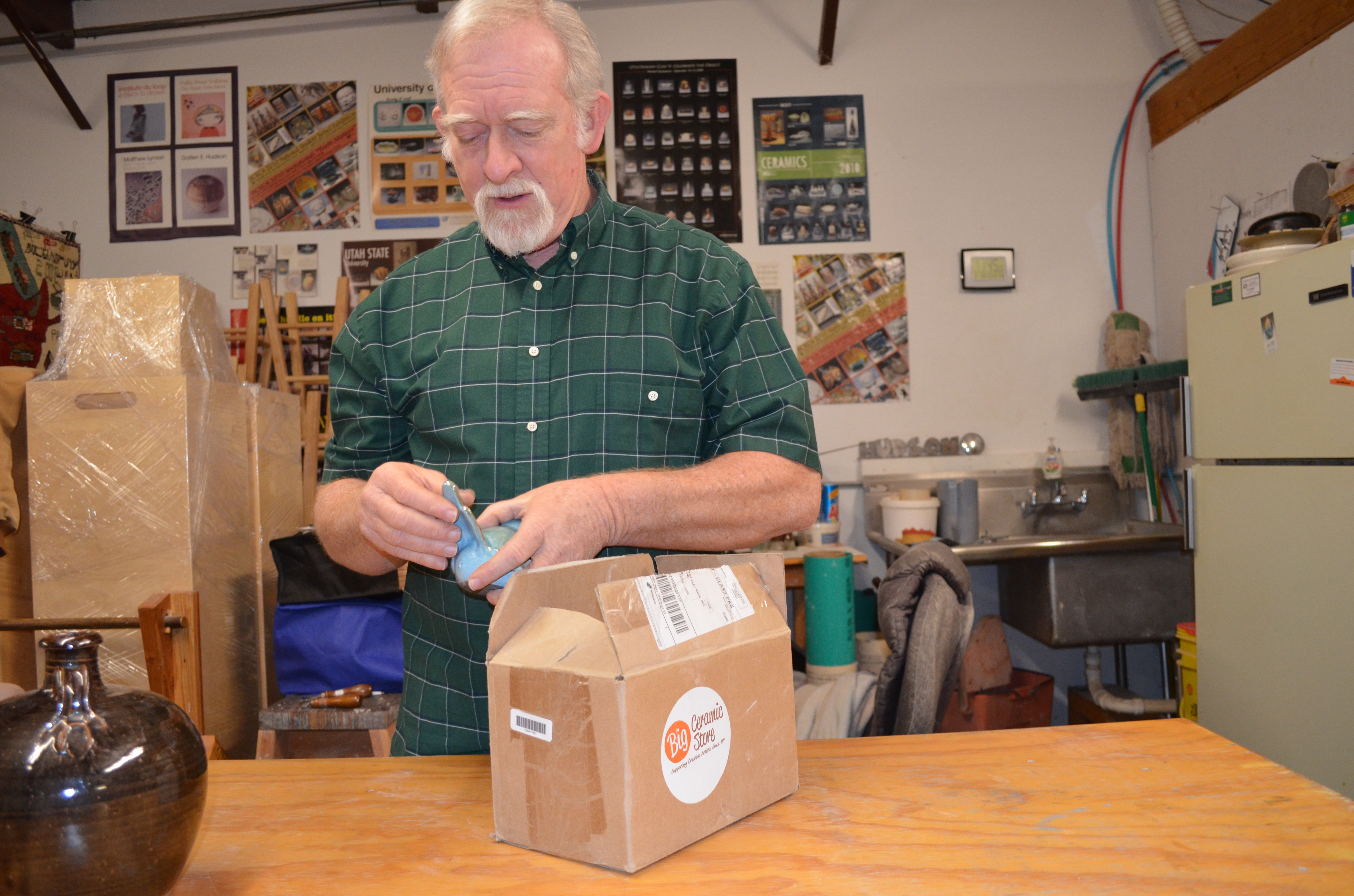 man in workshop holding pottery