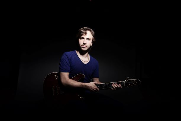 man holding guitar in dark setting
