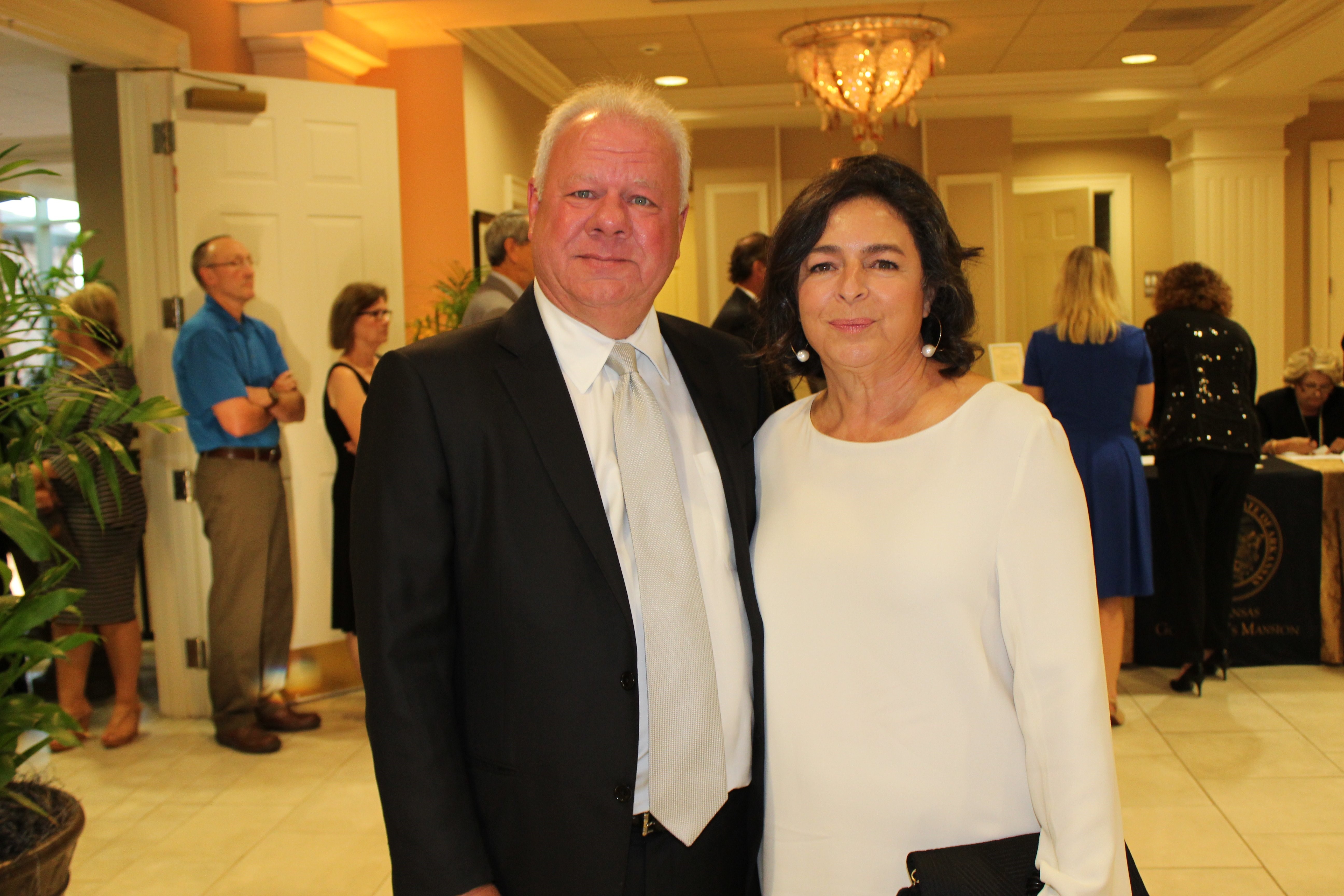 profile view of man in suit and woman wearing earrings standing next to each other in tiled room
