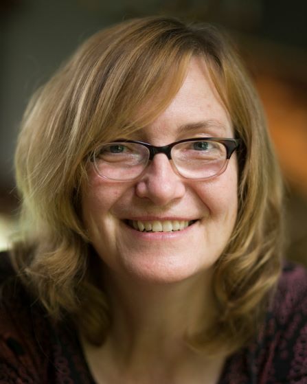 headshot of woman smiling and wearing glasses