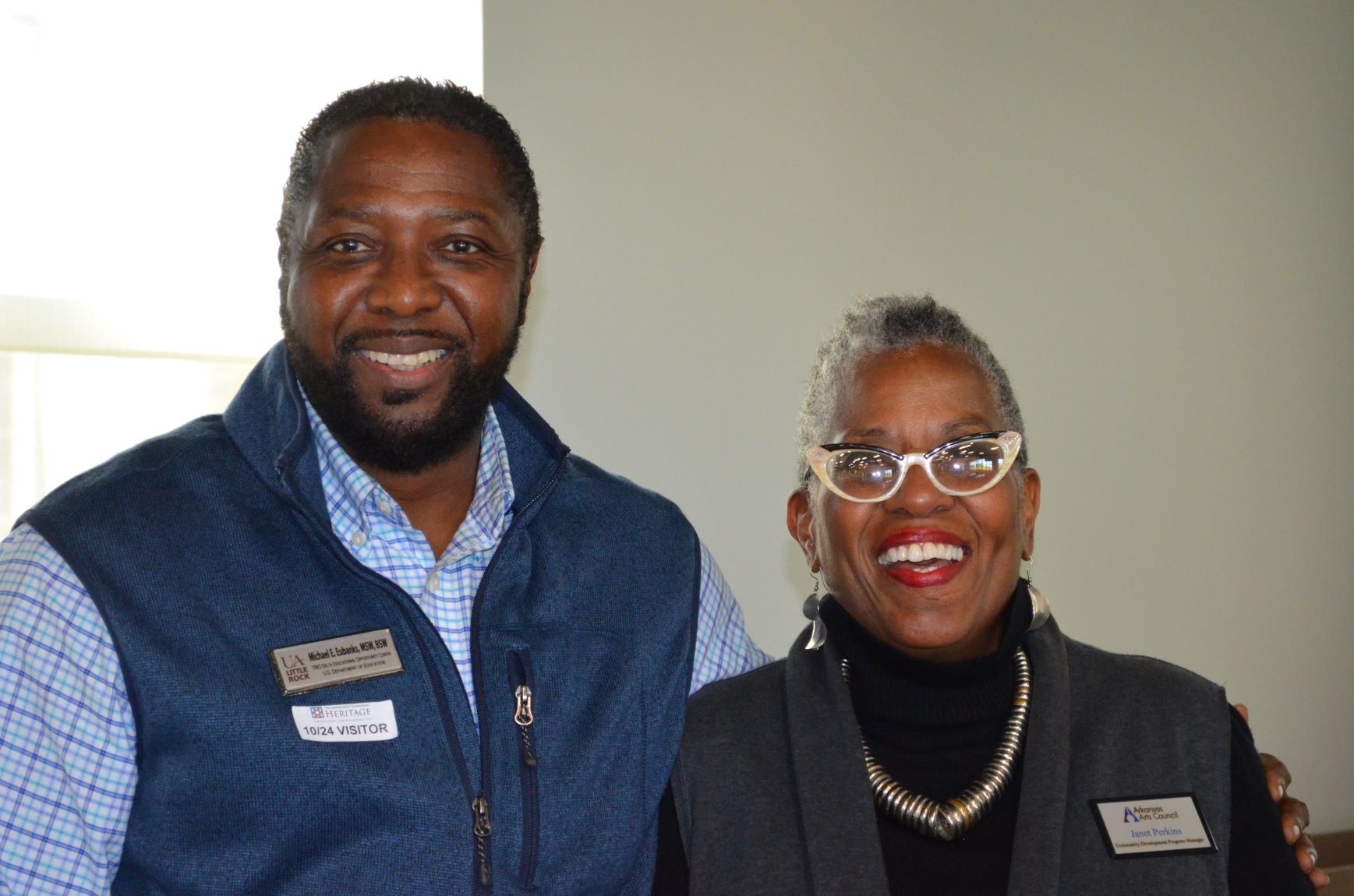 man and woman wearing nametags standing next to each other smiling at camera