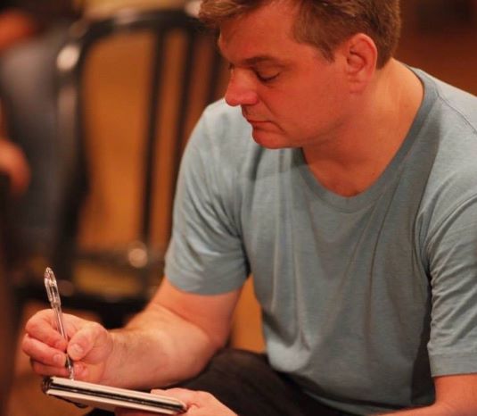 man sitting and writing on notebook
