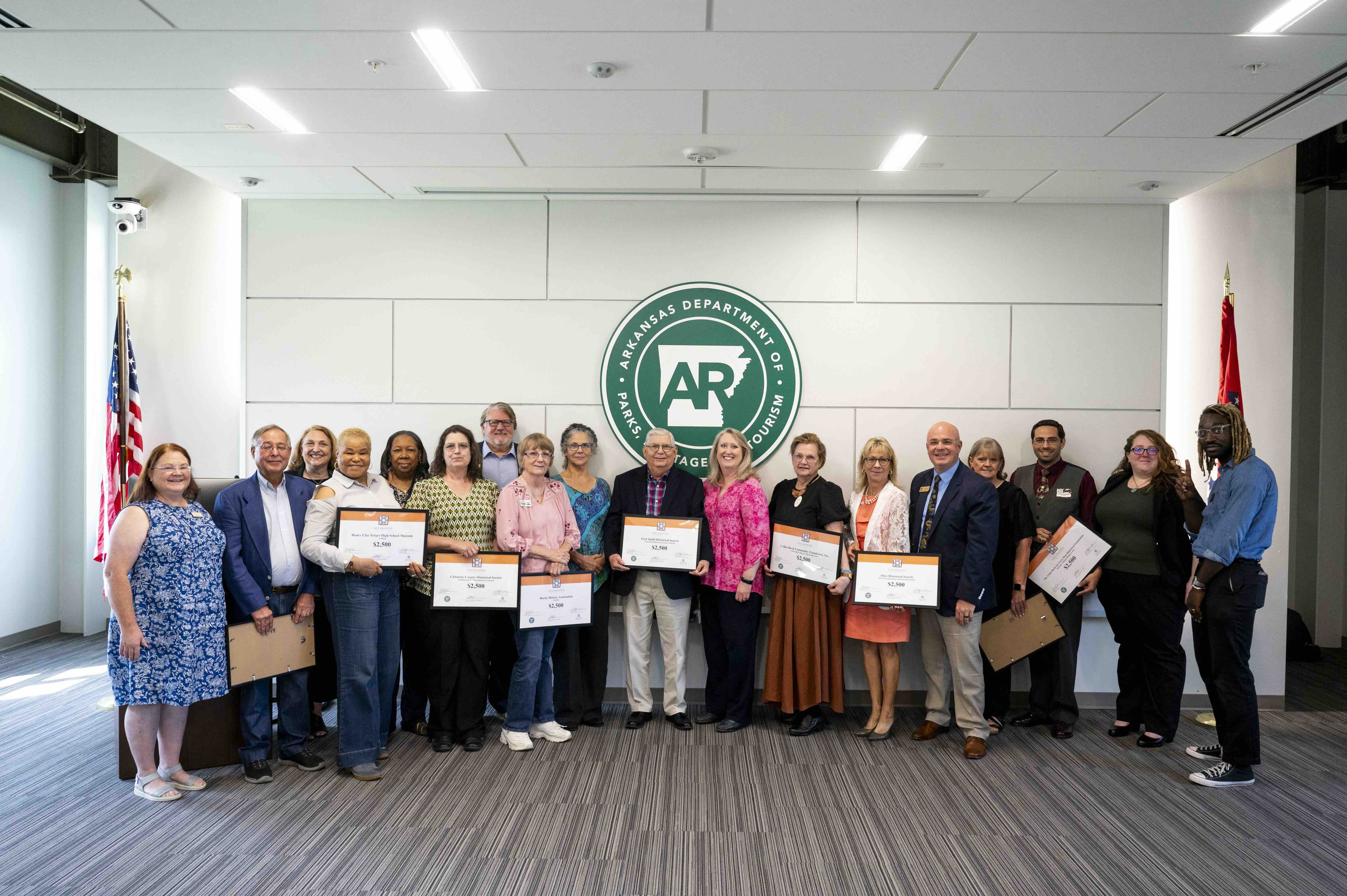 Grants1 A group of grant recipients holding framed certificates posing in front of a large white wall.