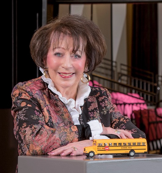 woman smiling with small model schoolbus