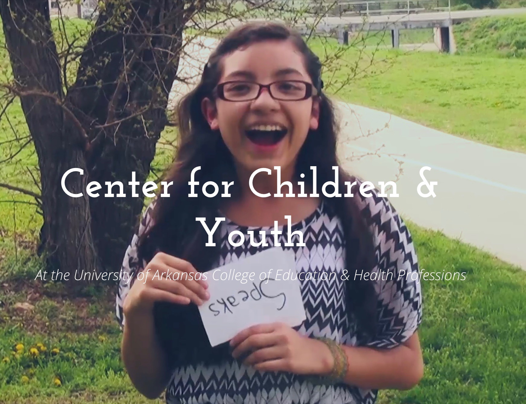 girl with glasses laughing and holding upside down sign that says 