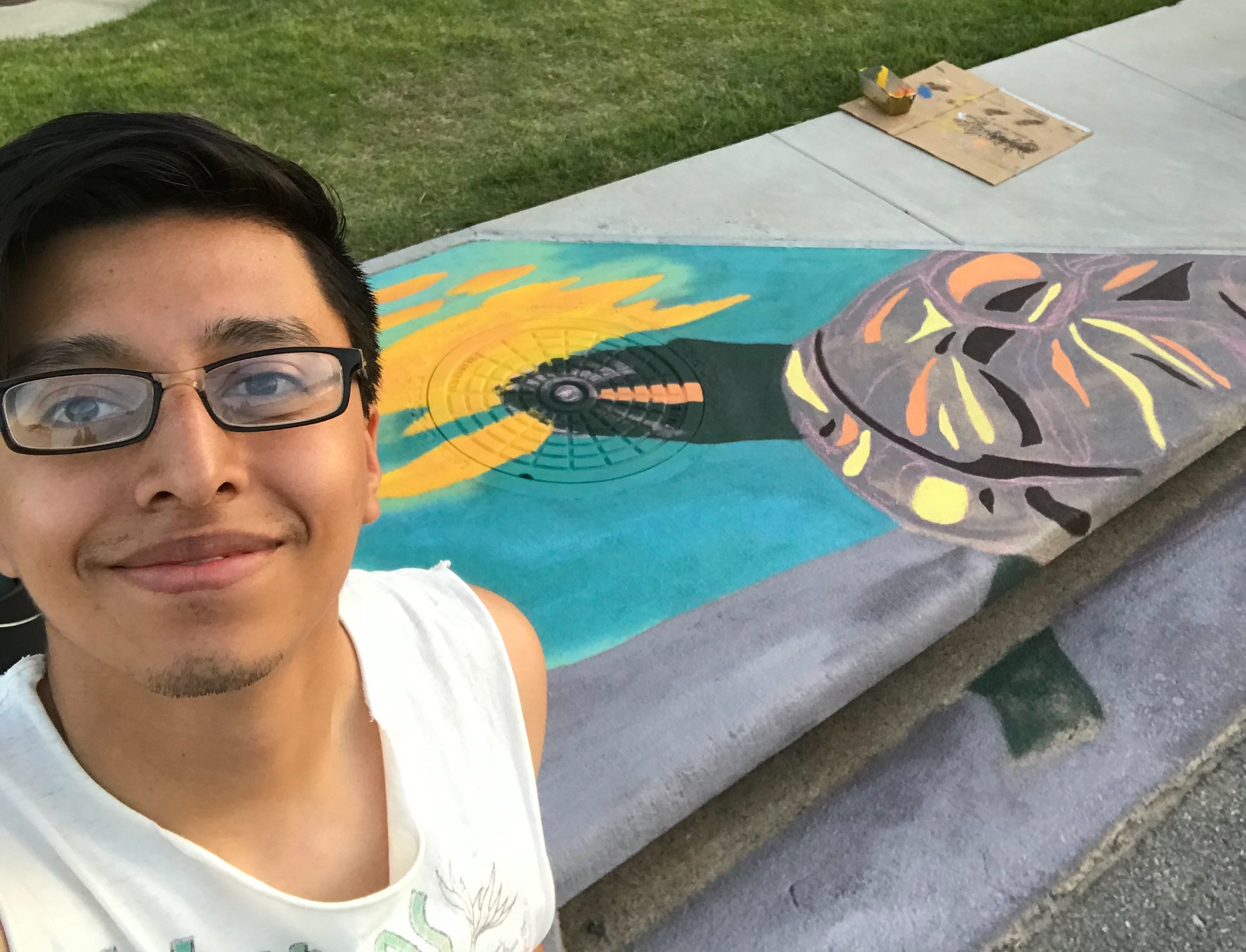 young man next to storm drain with colorful painting of turtle on it