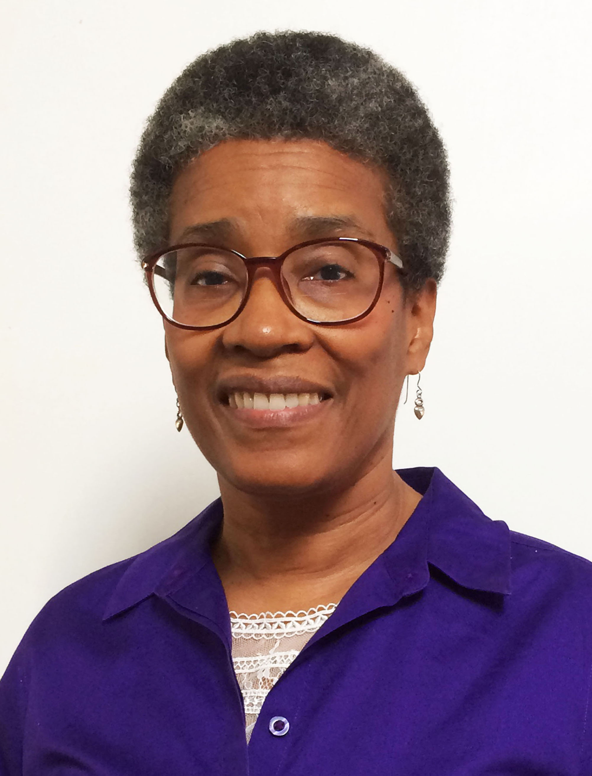 headshot of woman with short hair wearing glasses and earrings