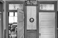 Facingawallwithtwodoorsandaclockinthecenterwiththeleftdooropenshowingtablesandchairs