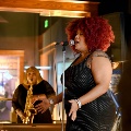 Awomansinginginablackpolkadotsparkledresswithanotherwomanbehindherplayingsaxophone