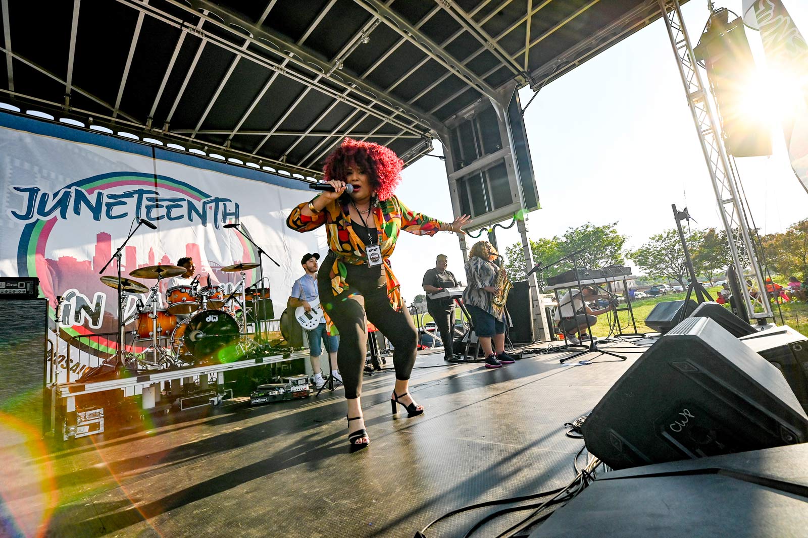 Woman singing on stage with a live band behind her.