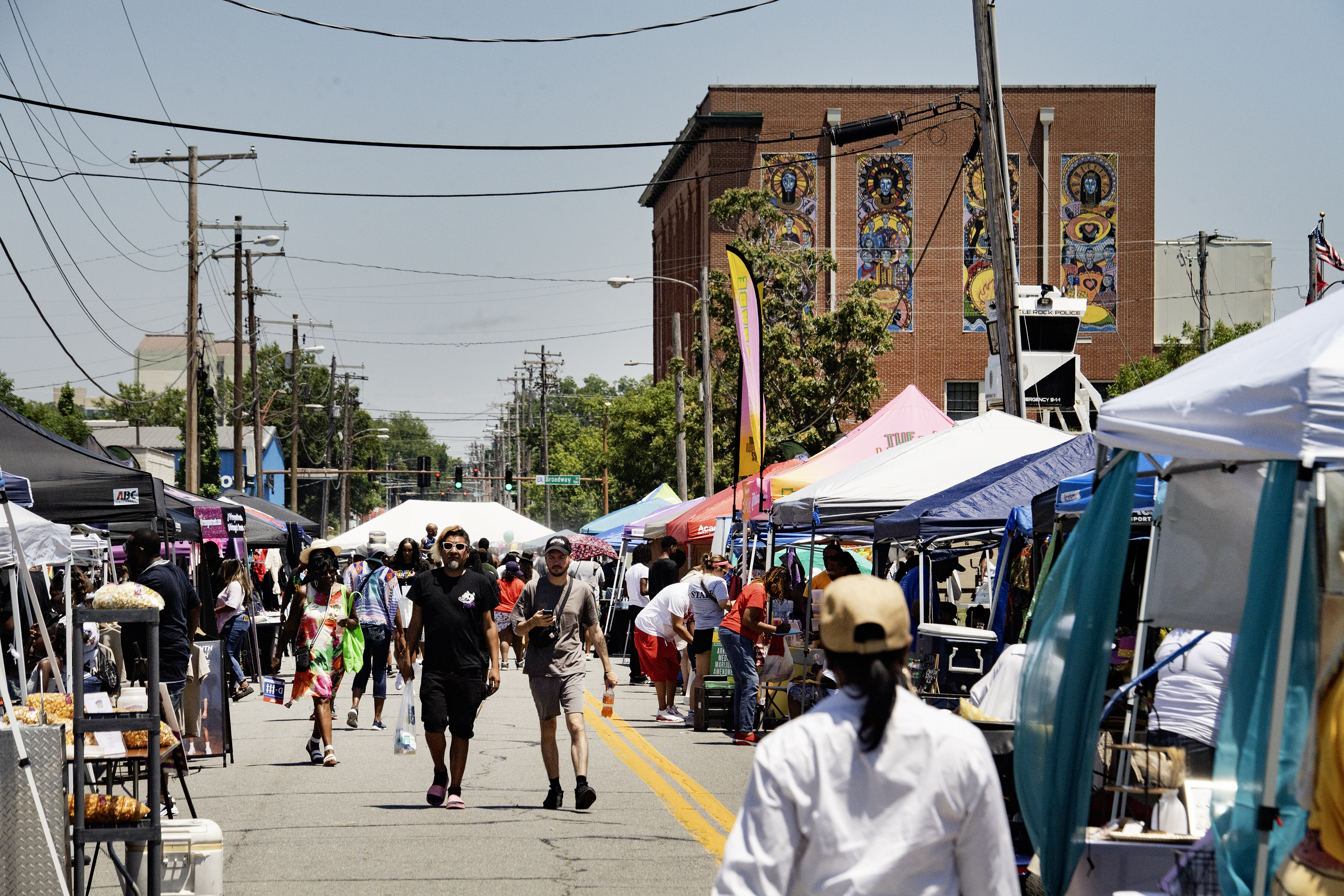 Peoplewalkbetweenboothsofvendorssellingvariousitemsandfood