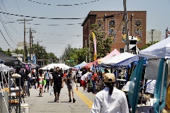 Peoplewalkbetweenboothsofvendorssellingvariousitemsandfood