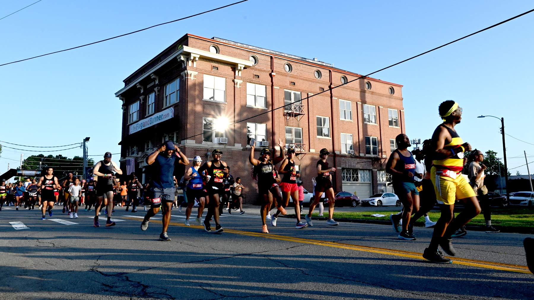 A group of contestants in athletic wear running past a building in a race.