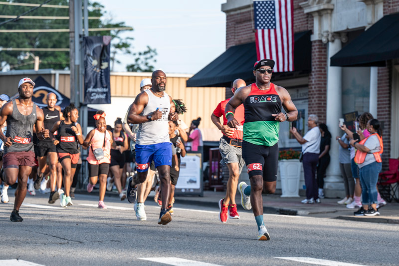 A group of people running in a race in the street.