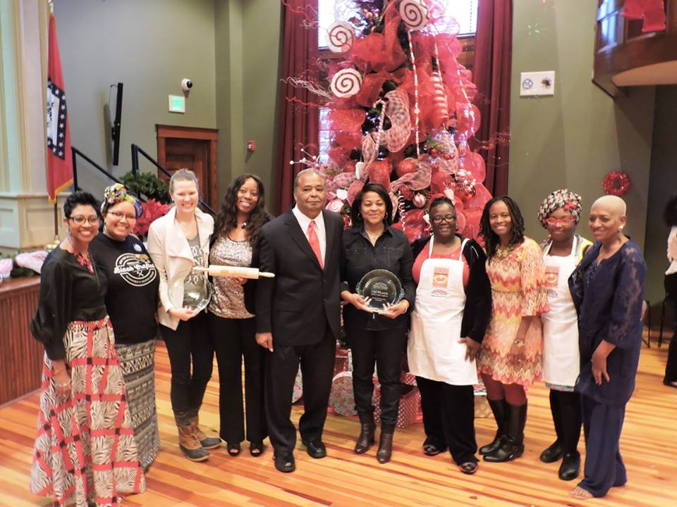 womenandmanstandinginfrontoflargeChristmastreeholdingrollingpinandpieplate