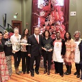 womenandmanstandinginfrontoflargeChristmastreeholdingrollingpinandpieplate