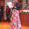 womaninredandzebra-printdressholdingpaperandspeakingintomicrophone