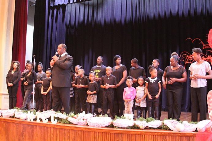groupofpeoplestandingonstagebehindmanholdingmicrophone