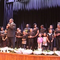 groupofpeoplestandingonstagebehindmanholdingmicrophone