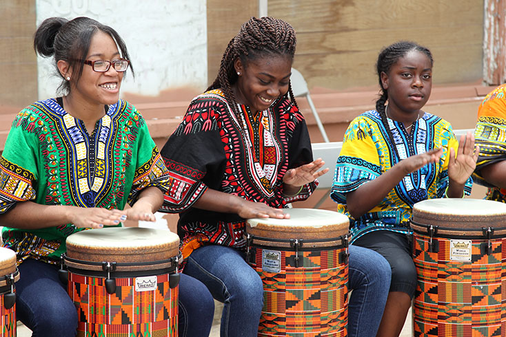 girlsinculturaloutfitssittinginarowdrumming