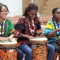 girlsinculturaloutfitssittinginarowdrumming