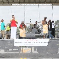 variouspeopleonstagetalkingsingingsigningandplayingdrumsandkeyboard
