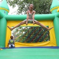 girljumpingingreenbouncecastlewithotherchildrenonlooking