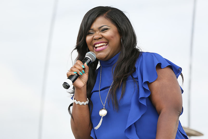 womaninblueshirtholdingmicrophonesmilingandsinging