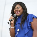womaninblueshirtholdingmicrophonesmilingandsinging