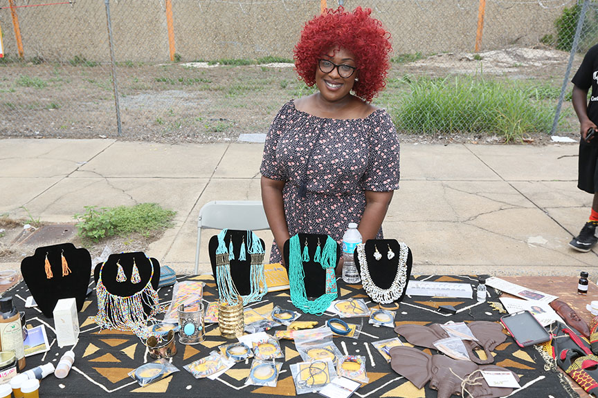 womanwithredhairsellingjewelryattableoutside