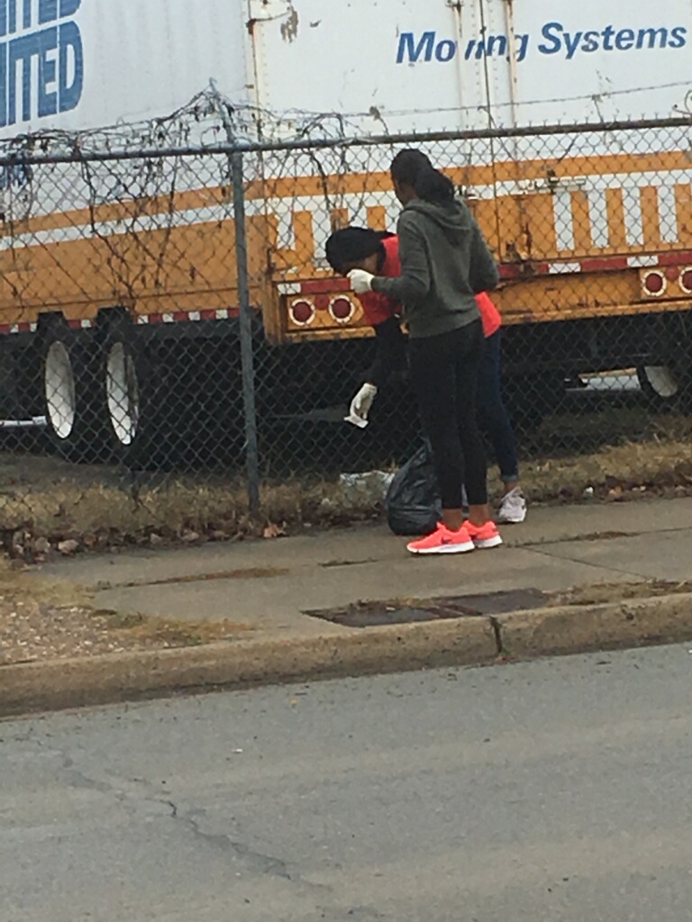 peopleonsidewalkbymetalfencepickinguptrash