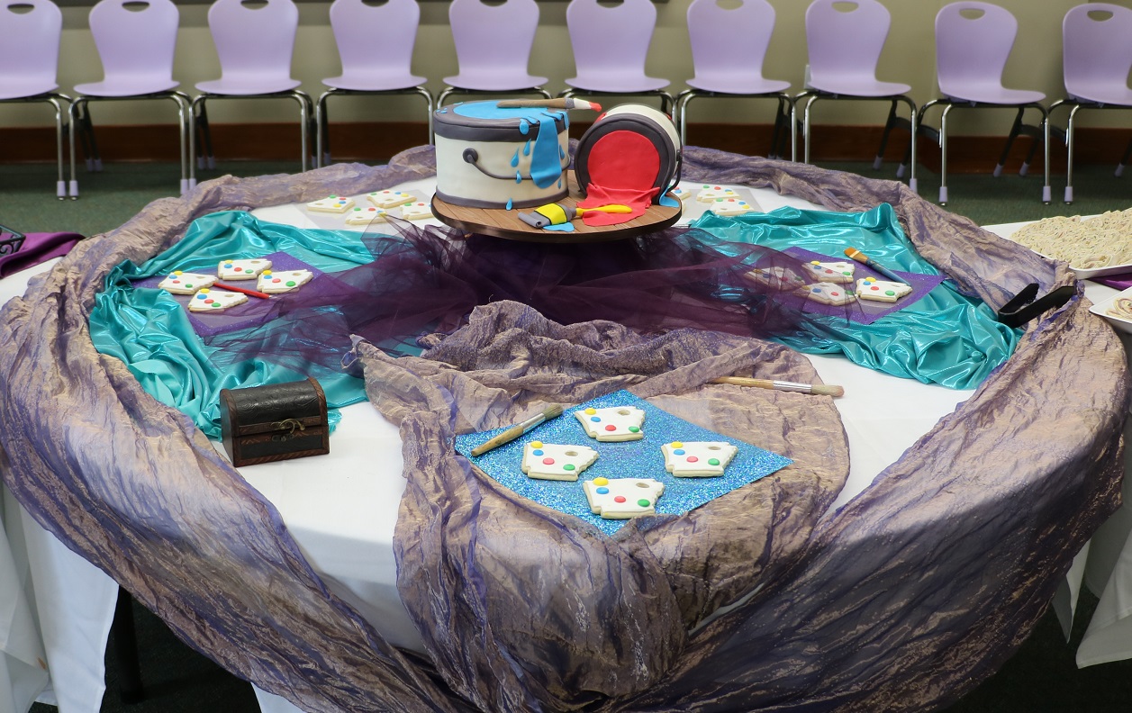 circulartablewithcakeinthecenterdesignedlikebucketsofpaintwithplatesofArkansas-shapedcookies