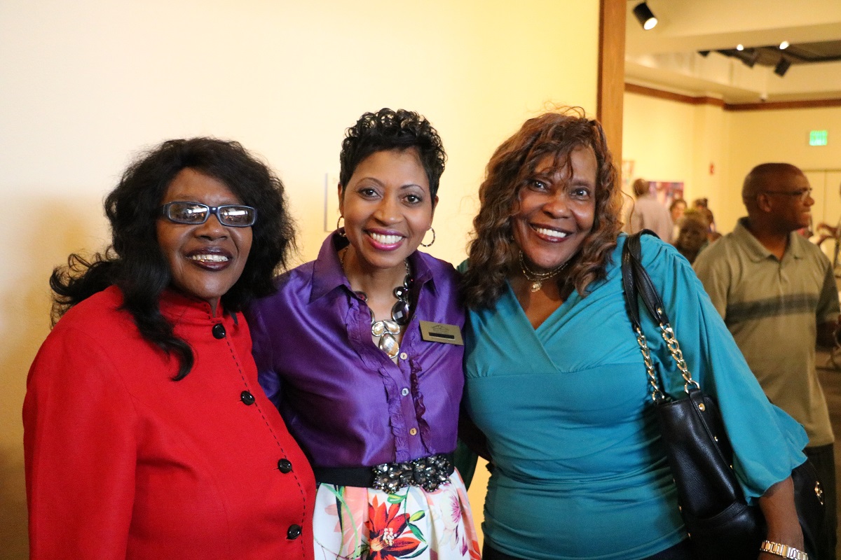 womenstandingtogethersmilingatexhibit