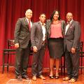 fourpeopledressedinpantsandskirtstandingtogethersmiling