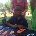 youngboysmilingwhilewomanadjustspastanecklacearoundhisneck