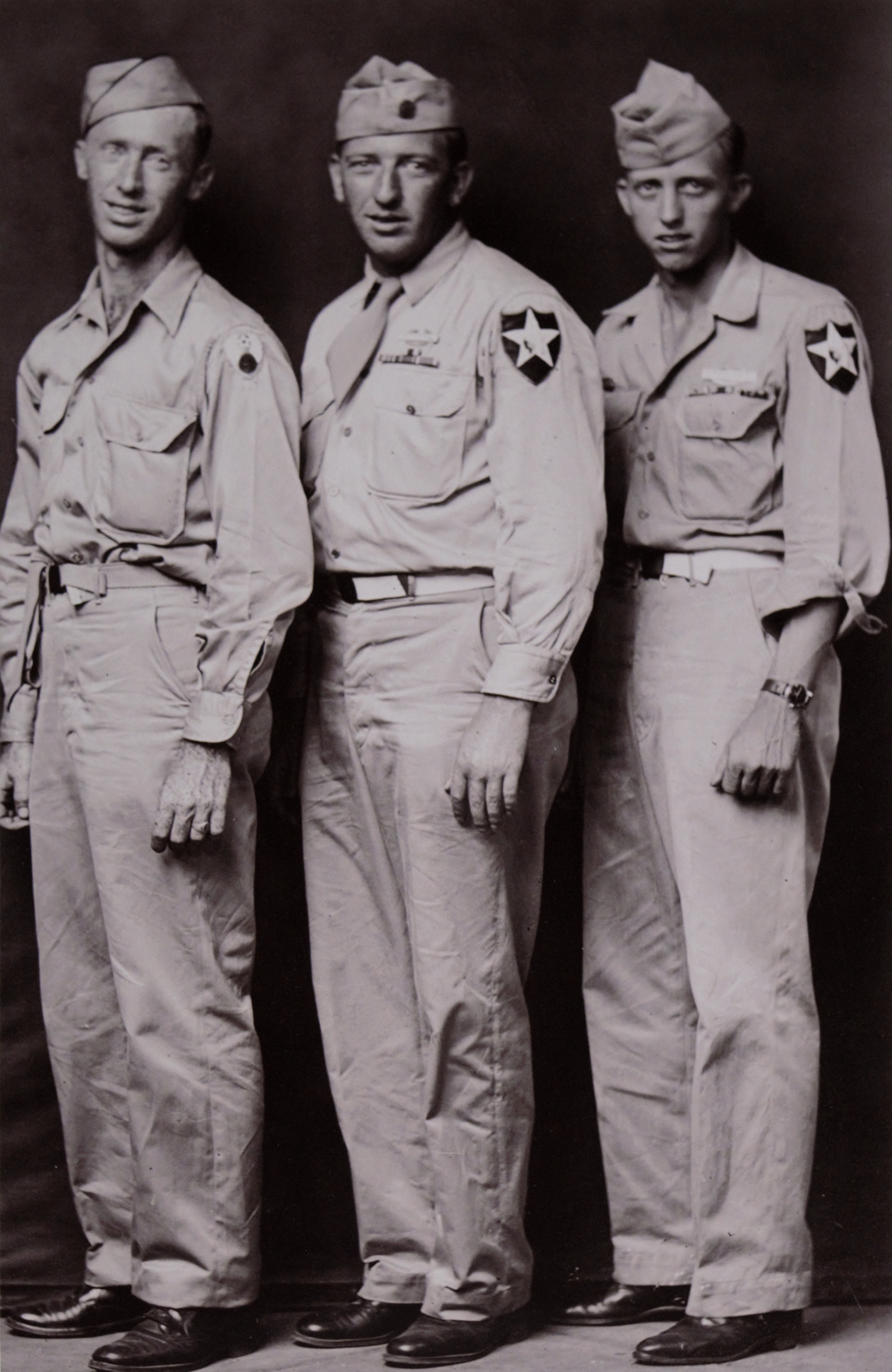 Three men stand side by side in uniform posing against a dark backdrop.