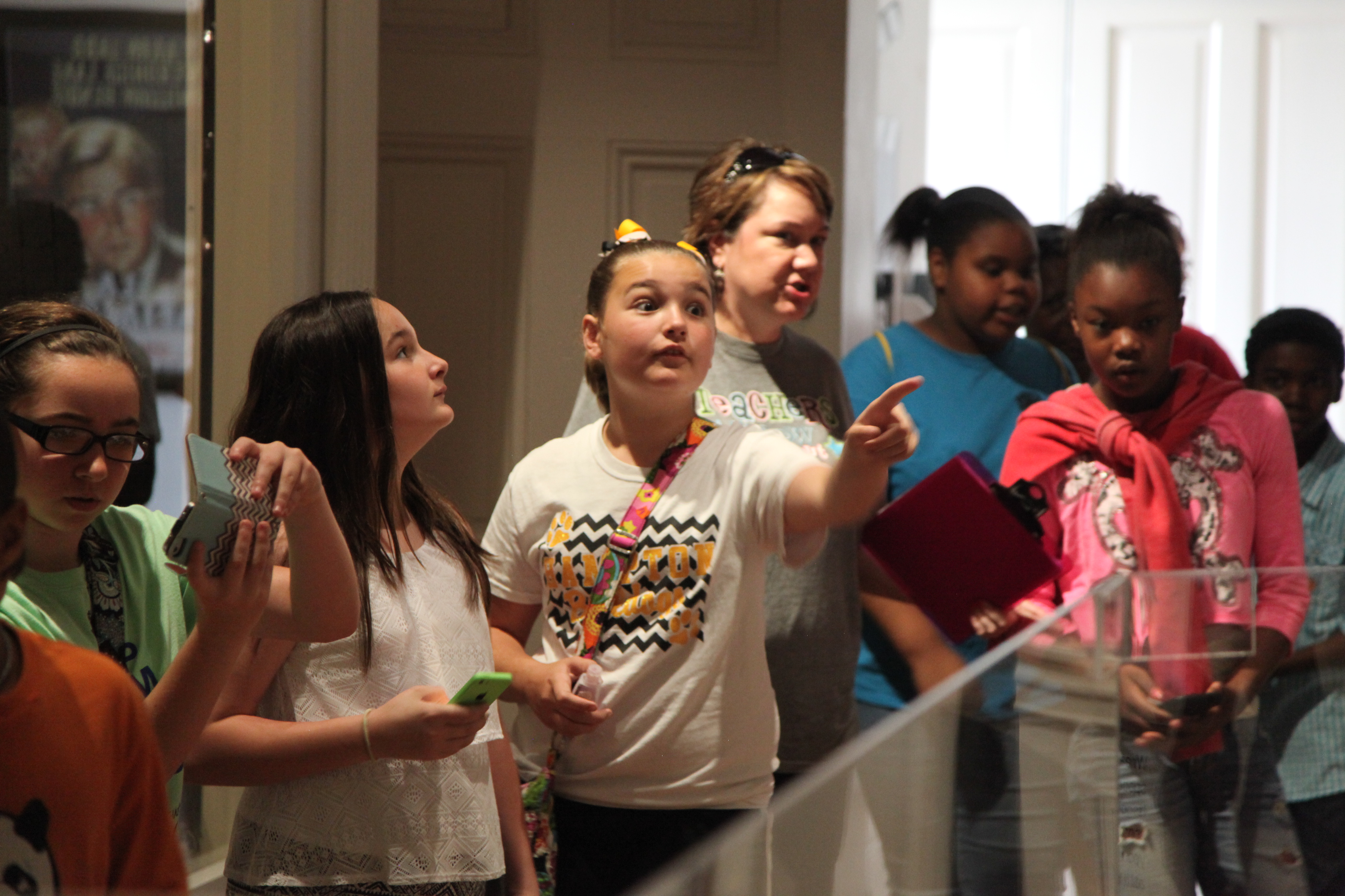 children standing around glass exhibits looking and pointing